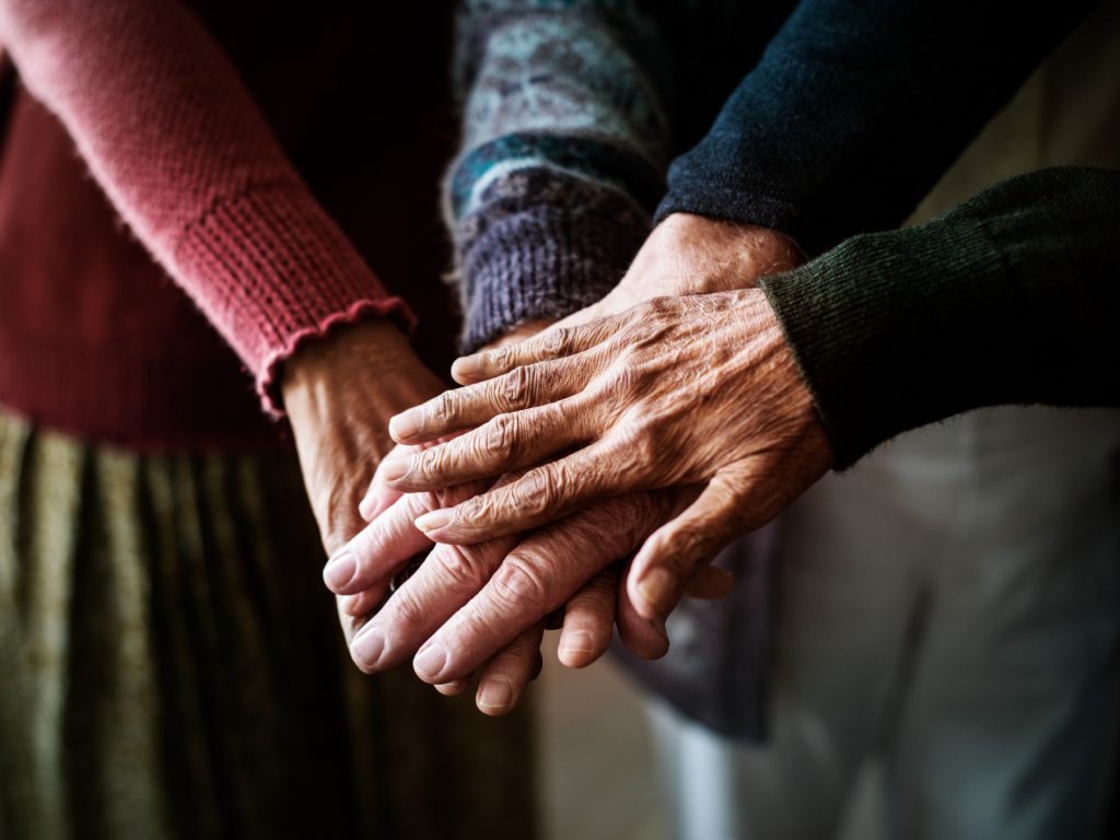Senioren halten Ihre Hände in die Mitte übereinander.